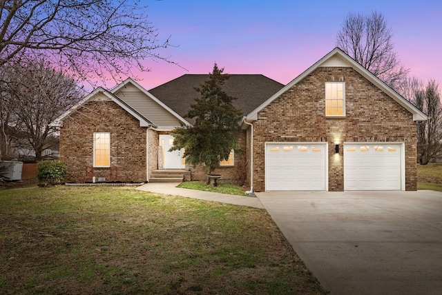 view of front facade with entry steps, brick siding, a lawn, and driveway