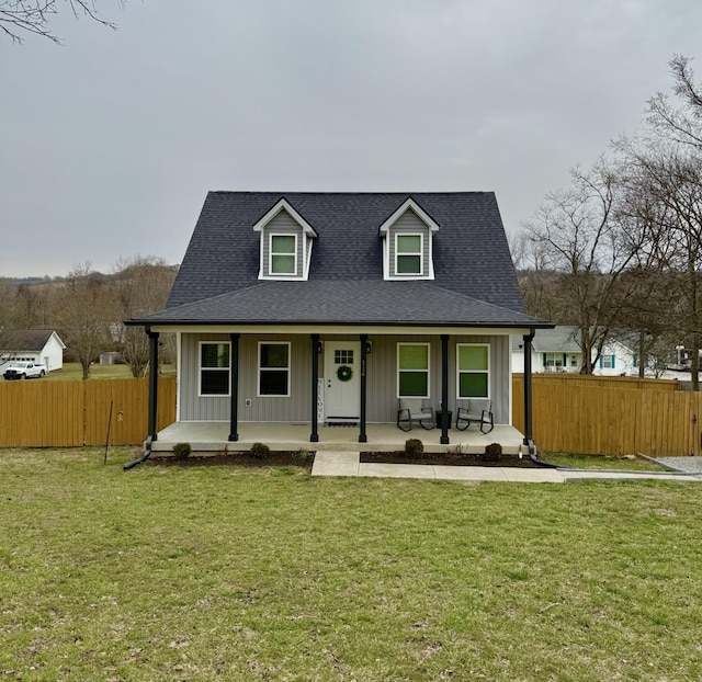 view of front of house with a porch, board and batten siding, a front lawn, and fence