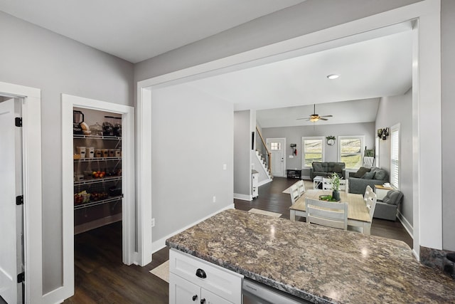 kitchen featuring dark wood-type flooring, baseboards, ceiling fan, dark stone countertops, and white cabinets