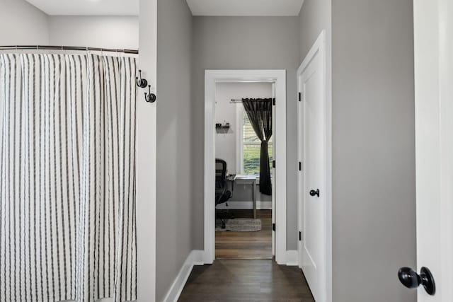 hall with dark wood-type flooring and baseboards