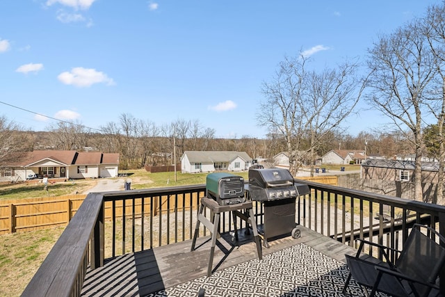 deck featuring a residential view, a lawn, a grill, and fence