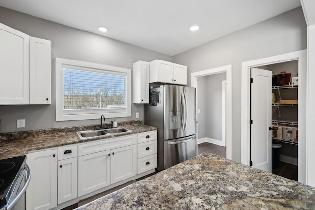 kitchen with dark stone counters, recessed lighting, a sink, stainless steel appliances, and white cabinetry