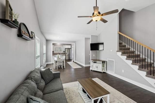 living room with visible vents, baseboards, stairway, wood finished floors, and high vaulted ceiling