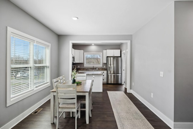 dining area featuring visible vents, baseboards, and dark wood-style flooring