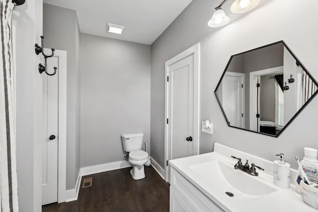 bathroom with baseboards, toilet, wood finished floors, and vanity