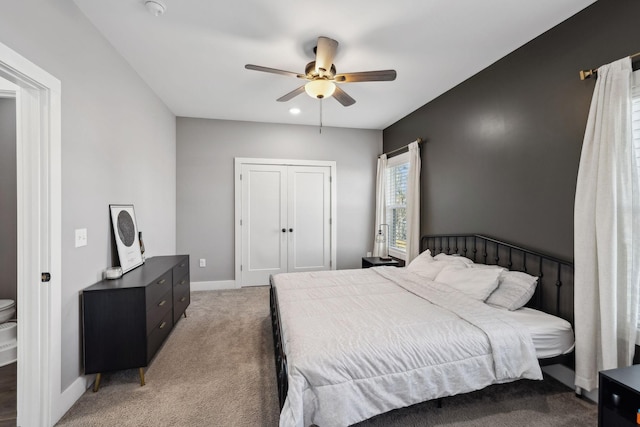 bedroom featuring a ceiling fan, light colored carpet, baseboards, and a closet