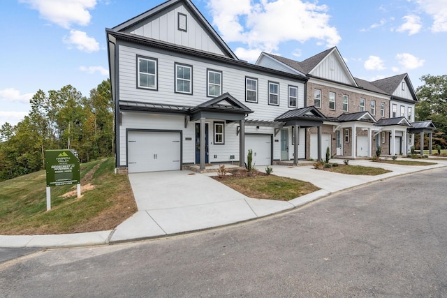 townhome / multi-family property featuring metal roof, driveway, board and batten siding, a front lawn, and a standing seam roof