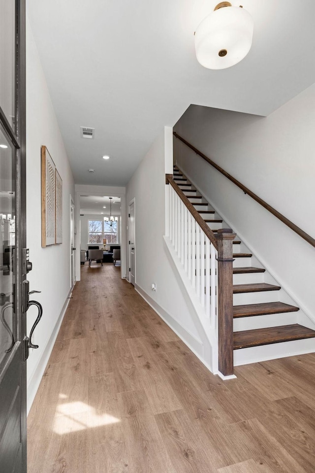 foyer with light wood-style floors, baseboards, stairs, and visible vents