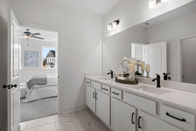 ensuite bathroom featuring marble finish floor, double vanity, a sink, and baseboards