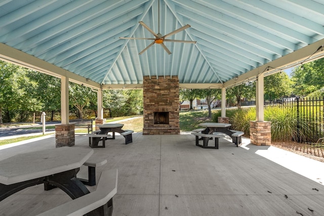 view of patio featuring fence, an outdoor stone fireplace, and a gazebo