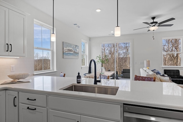 kitchen with a sink, open floor plan, light countertops, backsplash, and dishwasher