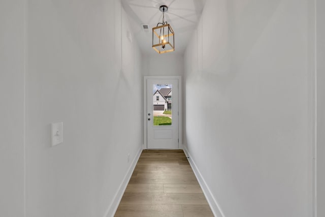 entryway featuring baseboards, an inviting chandelier, and light wood-style floors