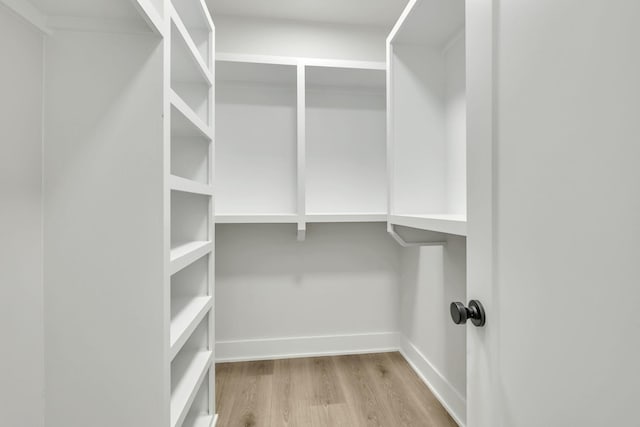 walk in closet with wood finished floors