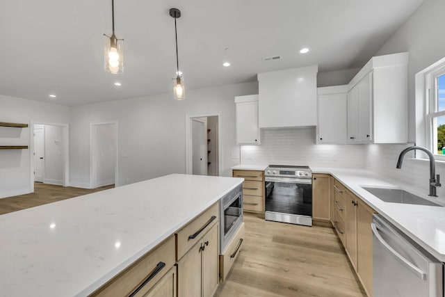 kitchen featuring visible vents, stainless steel appliances, light wood-type flooring, premium range hood, and a sink