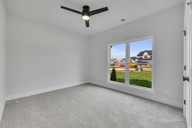 carpeted empty room with visible vents, a ceiling fan, and baseboards