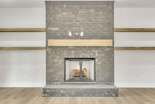 interior details with a brick fireplace, baseboards, and wood finished floors