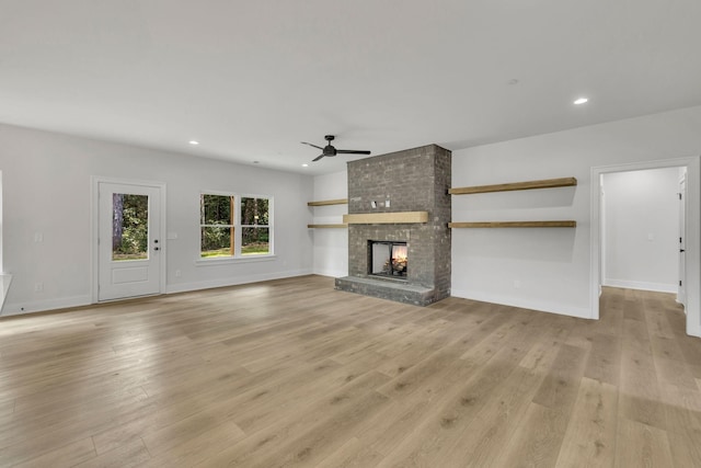 unfurnished living room featuring a brick fireplace, light wood-style flooring, a ceiling fan, and recessed lighting