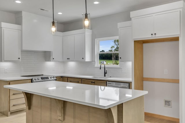 kitchen featuring light countertops, appliances with stainless steel finishes, a sink, and white cabinetry