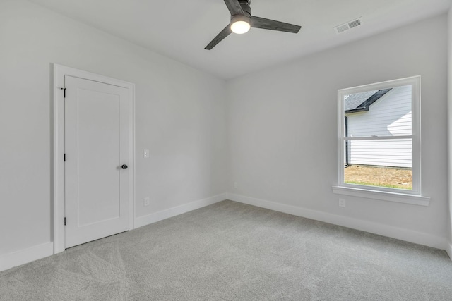 carpeted spare room with baseboards, visible vents, and a ceiling fan