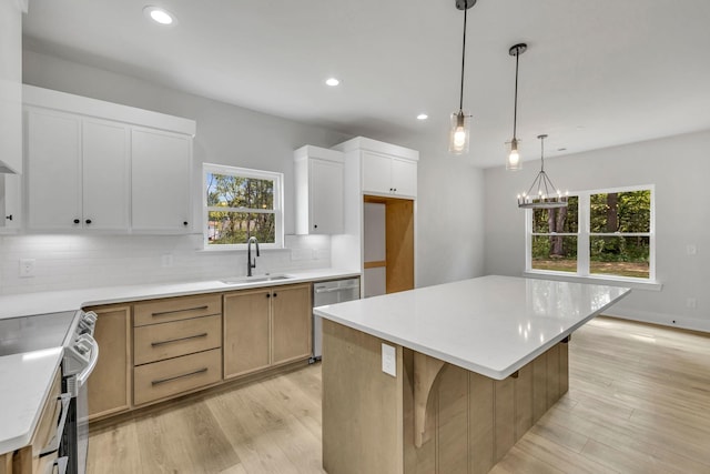 kitchen with appliances with stainless steel finishes, light wood-style floors, a sink, and tasteful backsplash