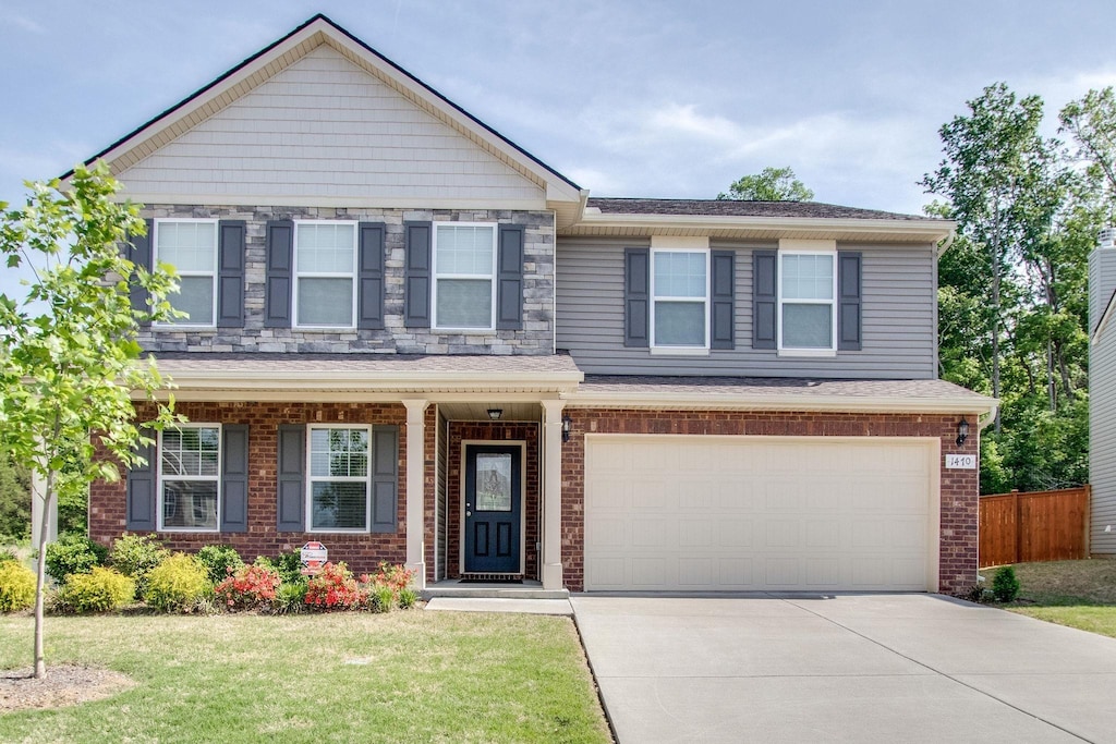 craftsman-style house with an attached garage, brick siding, fence, concrete driveway, and a front yard