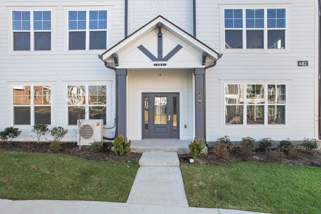 doorway to property featuring covered porch, ac unit, and a lawn