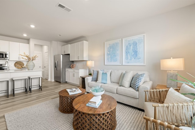 living area featuring light wood finished floors, visible vents, and recessed lighting