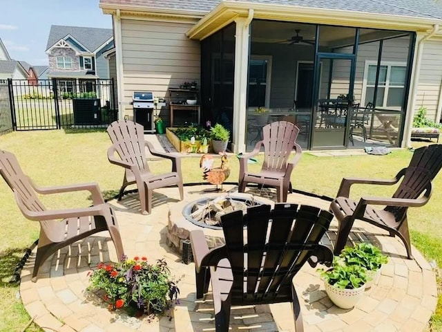 view of patio / terrace with a ceiling fan, fence, an outdoor fire pit, a grill, and a sunroom