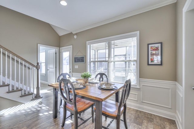 dining space with ornamental molding, wood finished floors, wainscoting, stairs, and vaulted ceiling