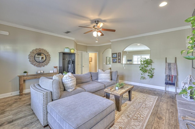 living area with baseboards, arched walkways, visible vents, and ceiling fan