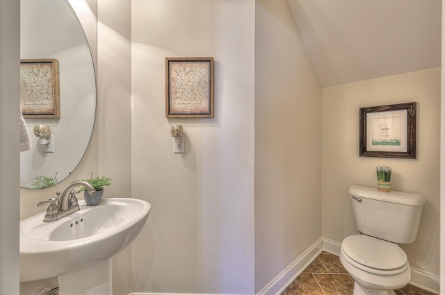 half bath featuring toilet, lofted ceiling, baseboards, and a sink