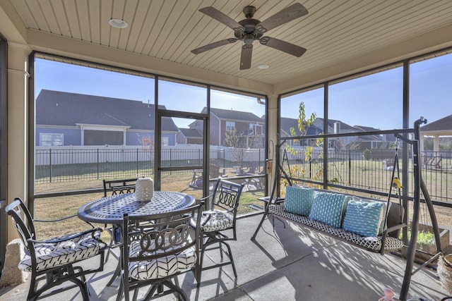 sunroom / solarium with a residential view and ceiling fan