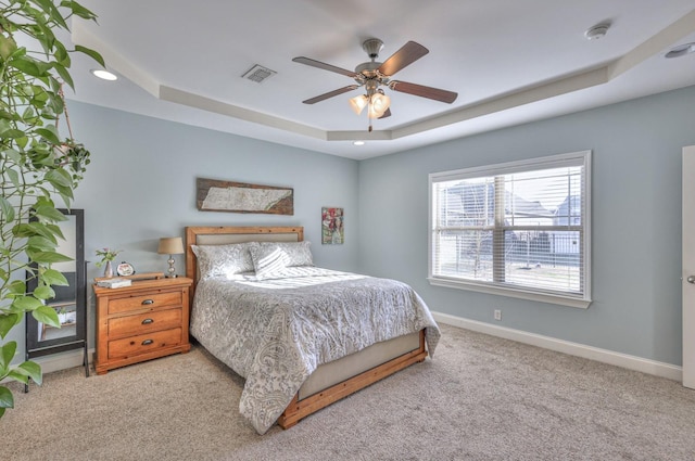 carpeted bedroom featuring visible vents, a raised ceiling, baseboards, and ceiling fan