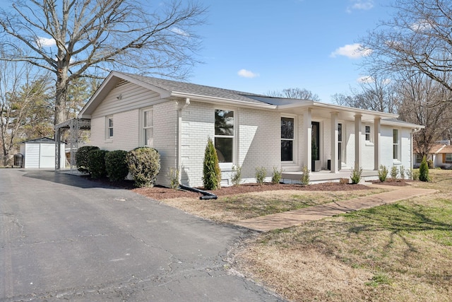 view of front of house featuring an outbuilding, brick siding, and a porch