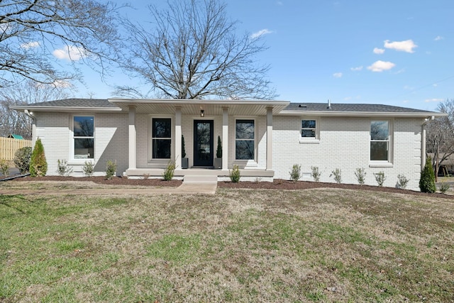 view of front of property featuring a porch, a front yard, brick siding, and roof with shingles