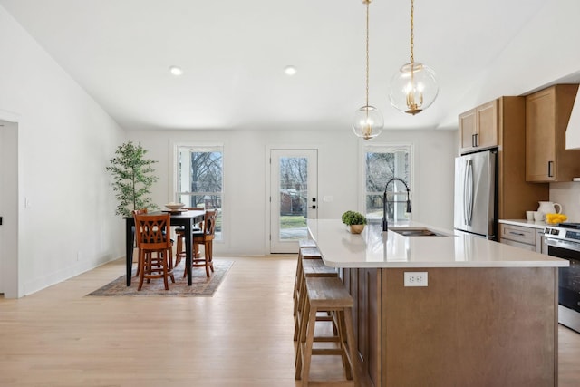 kitchen with stainless steel appliances, light wood-style floors, light countertops, and a sink