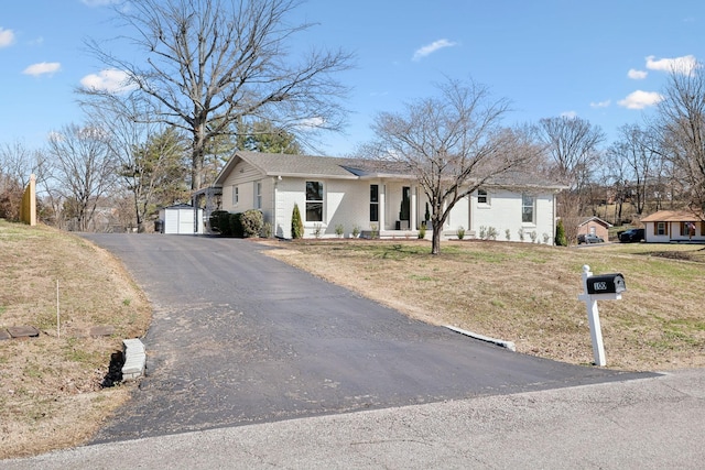 view of front facade featuring an outbuilding, brick siding, a front yard, and a garage