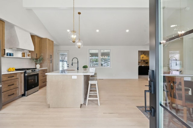 kitchen featuring custom range hood, stainless steel range with gas stovetop, vaulted ceiling with beams, light countertops, and a sink