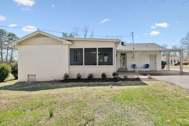 ranch-style home with a sunroom, a front lawn, and brick siding