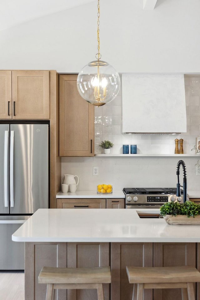 kitchen featuring appliances with stainless steel finishes, a breakfast bar, light countertops, and tasteful backsplash