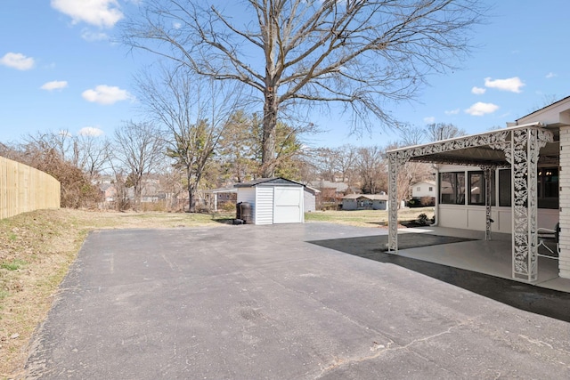 exterior space with a storage unit, a detached garage, and fence