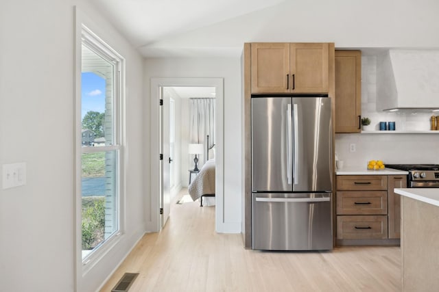 kitchen with plenty of natural light, visible vents, lofted ceiling, wall chimney exhaust hood, and stainless steel appliances