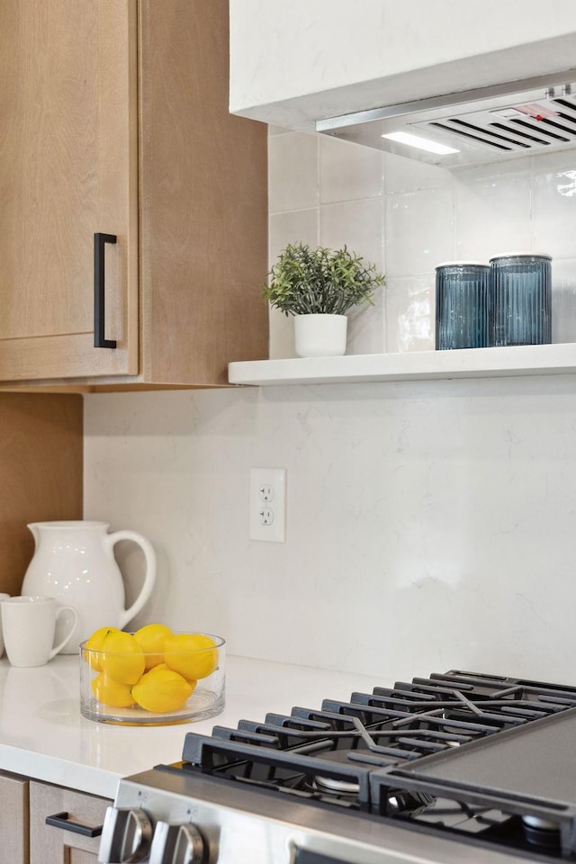 kitchen with light countertops, stainless steel gas range oven, backsplash, and light brown cabinetry