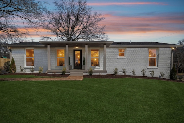 view of front of home featuring a porch, crawl space, brick siding, and a lawn