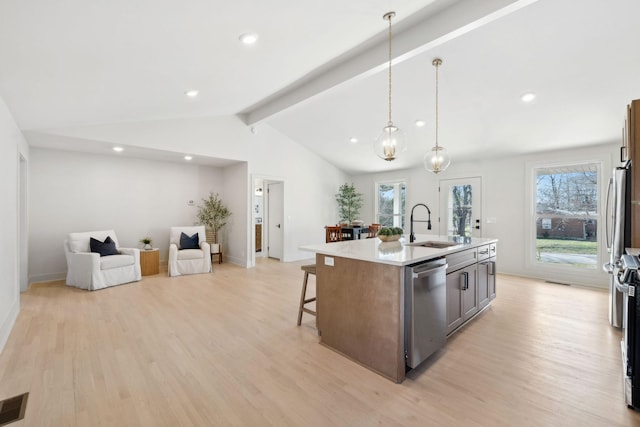 kitchen with lofted ceiling with beams, a breakfast bar area, stainless steel appliances, a sink, and light wood-type flooring