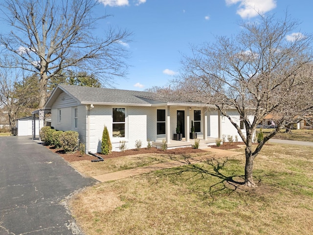 ranch-style house with brick siding, a front lawn, a porch, and an outdoor structure