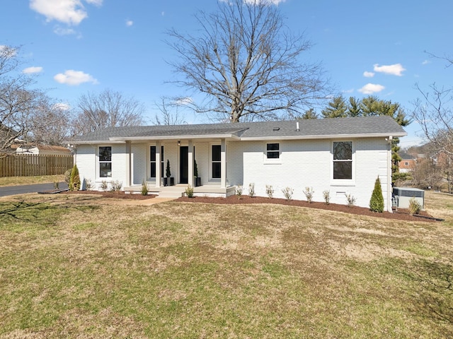 view of front of home with brick siding, covered porch, fence, and a front yard