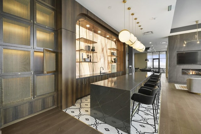 bar with expansive windows, decorative light fixtures, a sink, and light wood-style flooring