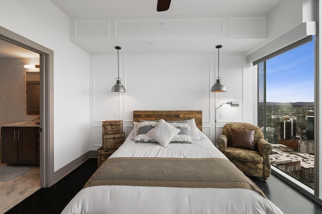 bedroom with baseboards, dark wood finished floors, a ceiling fan, connected bathroom, and a sink