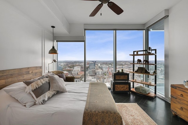 bedroom with a city view, ceiling fan, and wood finished floors